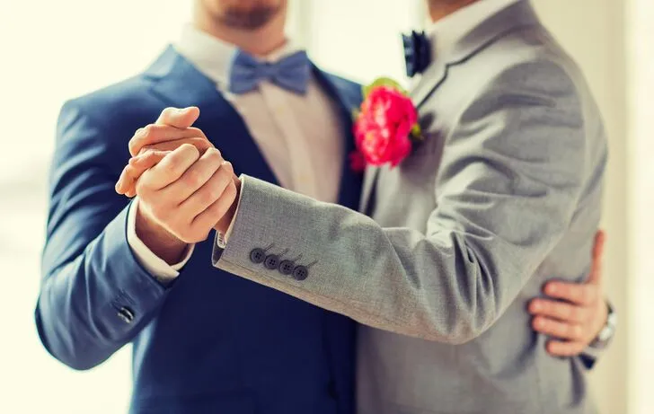 Two men in suits holding hands - representing love and self-discovery